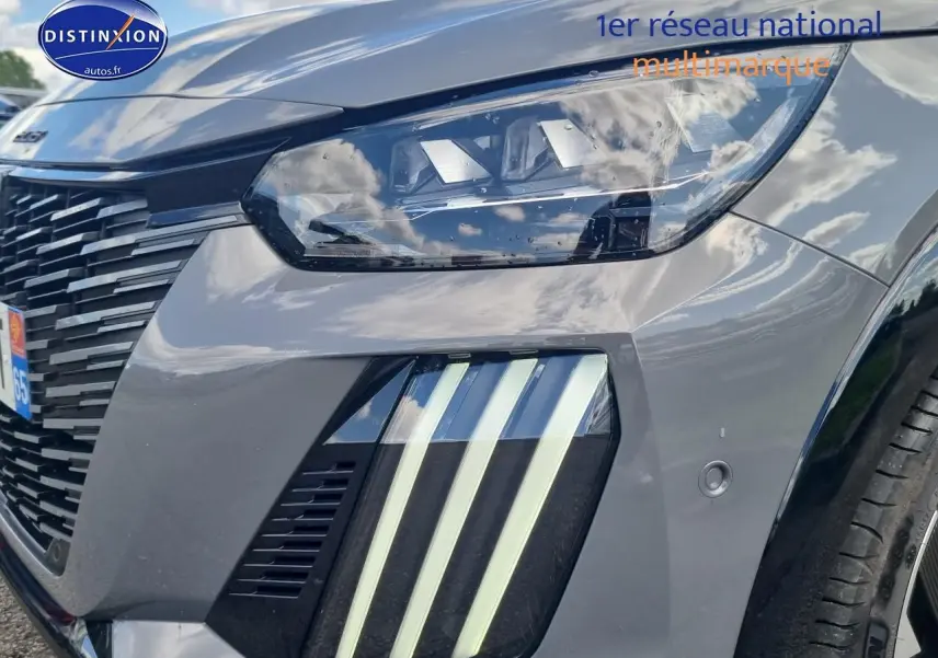 Gros plan sur l'avant droit gris d'une Peugeot 208 1.2 hybrid 136 GT avec phares et feux LED distinctifs.