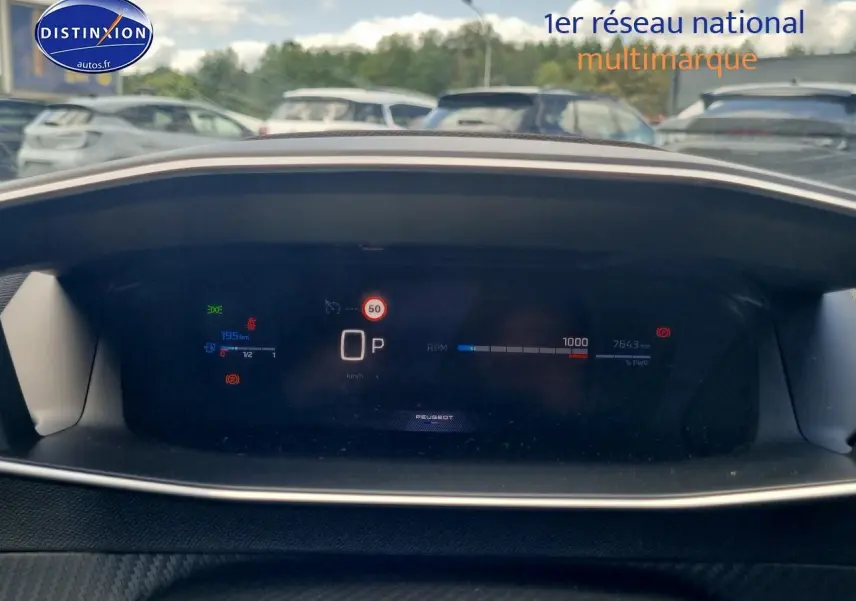 Tableau de bord numérique du Peugeot 208 gris, affichant la vitesse, la jauge et les alertes en vue frontale.