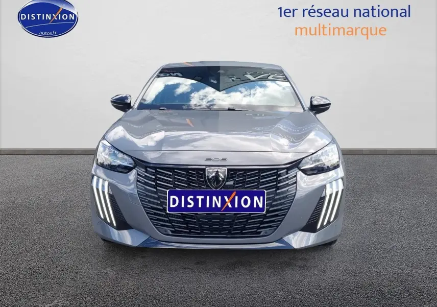 Vue frontale d'une Peugeot 208 gris métallisé avec calandre noire et feux diurnes à LED verticaux allumés.