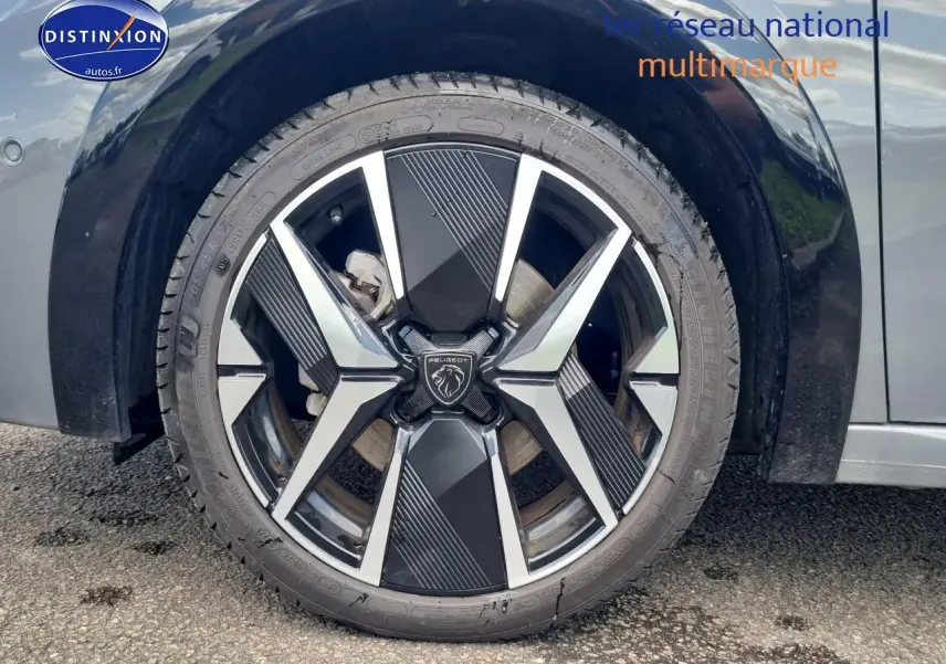 Gros plan sur la jante alu 17 pouces noire et argentée d'une Peugeot 208 gris côté avant droit.