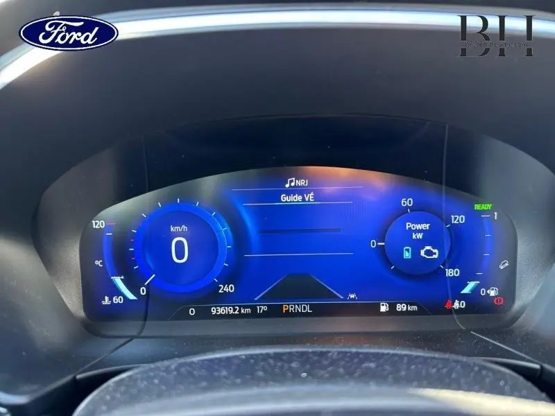 Tableau de bord numérique bleu du Ford Kuga hybride 2022 affichant vitesse, puissance et informations de conduite.