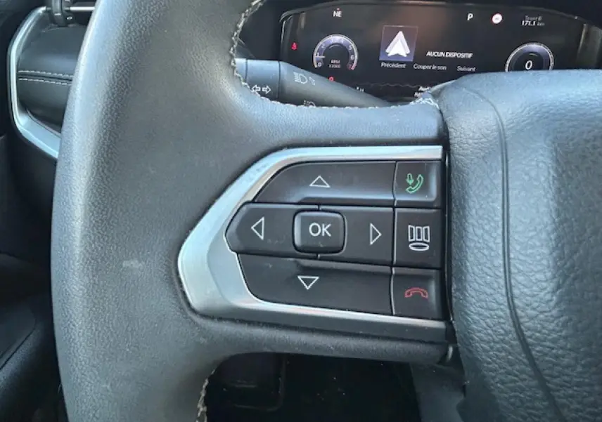 Gros plan sur les commandes gauche du volant noir du Jeep Compass 2021 avec affichage numérique en arrière-plan.