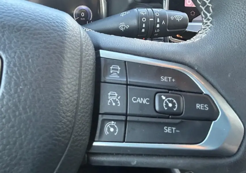 Gros plan sur les commandes de régulateur de vitesse au volant cuir noir du Jeep Compass 2021.