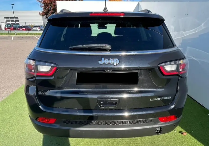 Vue arrière d'un Jeep Compass noir métallisé Limited avec feux LED et logo distinctif sur un parking extérieur.
