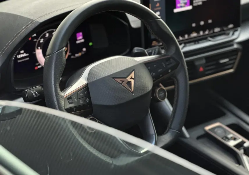 Intérieur du CUPRA Formentor 2025, vue rapprochée du volant cuir noir avec logo cuivre et tableau de bord digital.