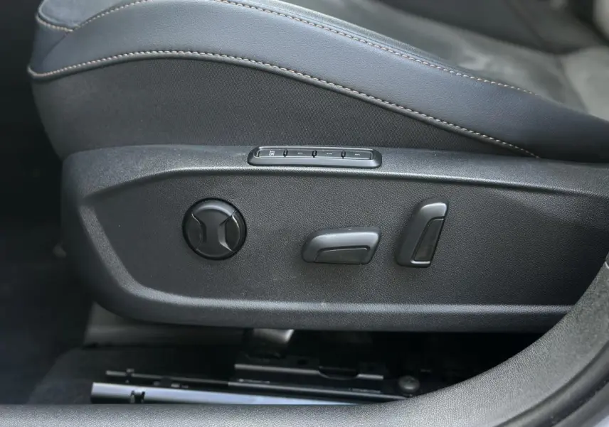 Gros plan sur les commandes électriques du siège conducteur noir suédine du CUPRA Formentor blanc Neige 2025.