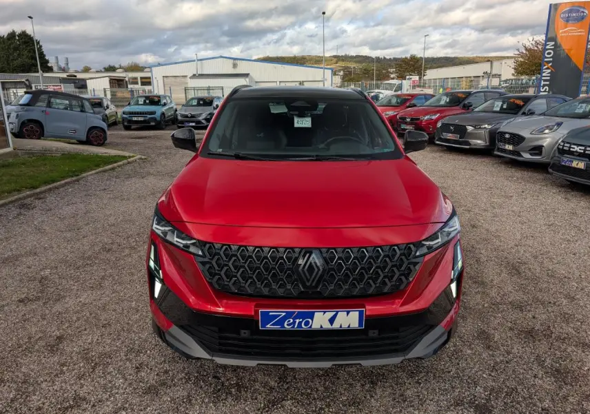 Vue avant d'un Renault Austral rouge métallisé avec calandre noire et feux LED distinctifs sur un parking.