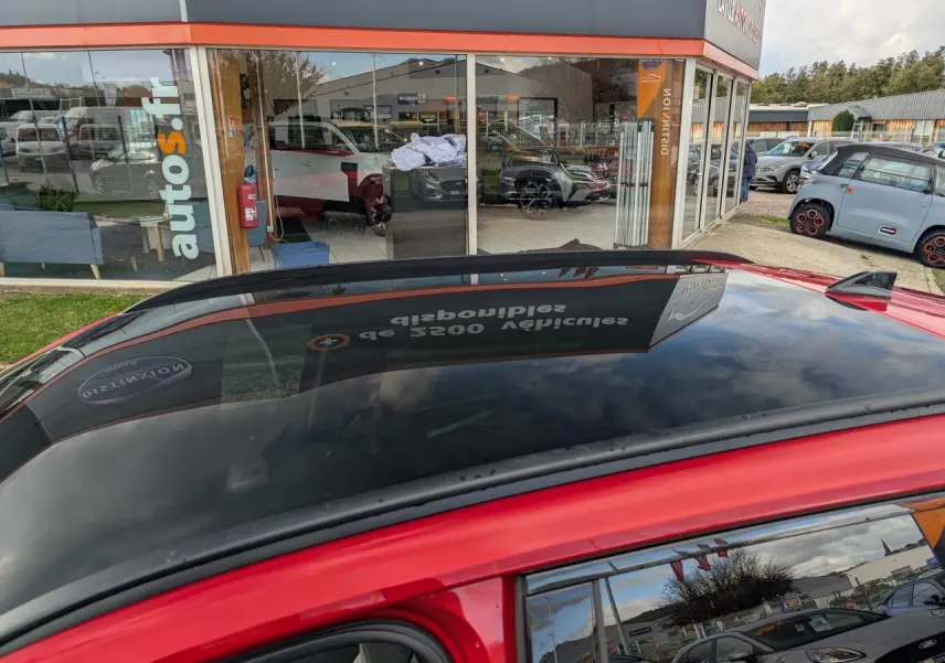 Toit panoramique en verre noir du Renault Austral rouge métallisé, vue rapprochée côté gauche du véhicule.