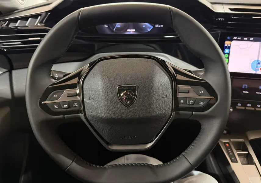 Vue centrée sur le volant cuir multifonctions de la Peugeot 308 BlueHDi 130 AUTO8 Allure, tableau de bord et écran tactile visibles.