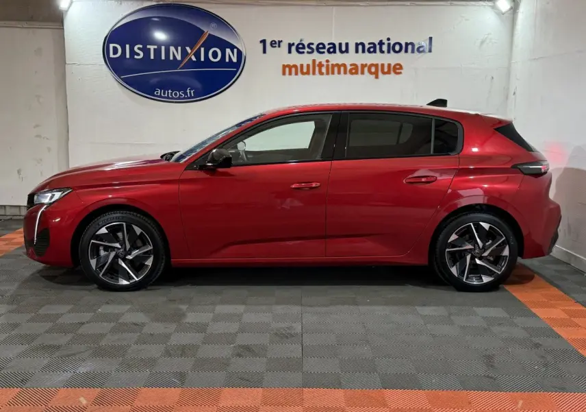 Profil latéral droit d'une Peugeot 308 rouge 2025, avec jantes alliage et vitres teintées, en intérieur showroom.