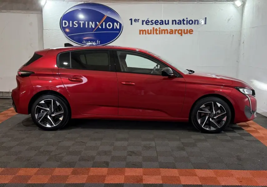 Profil droit de la Peugeot 308 rouge 2025 avec jantes alliage et lignes dynamiques en arrière-plan showroom.