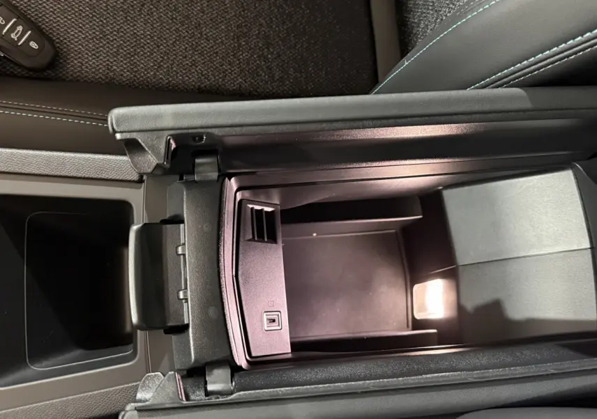 Vue plongeante sur le rangement central ouvert de la Peugeot 308 rouge, intérieur noir avec éclairage LED intégré.