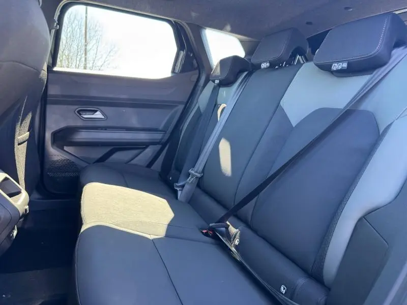 Vue latérale intérieure de la banquette arrière noire et grise du Dacia Duster 2025 avec ceintures de sécurité visibles.