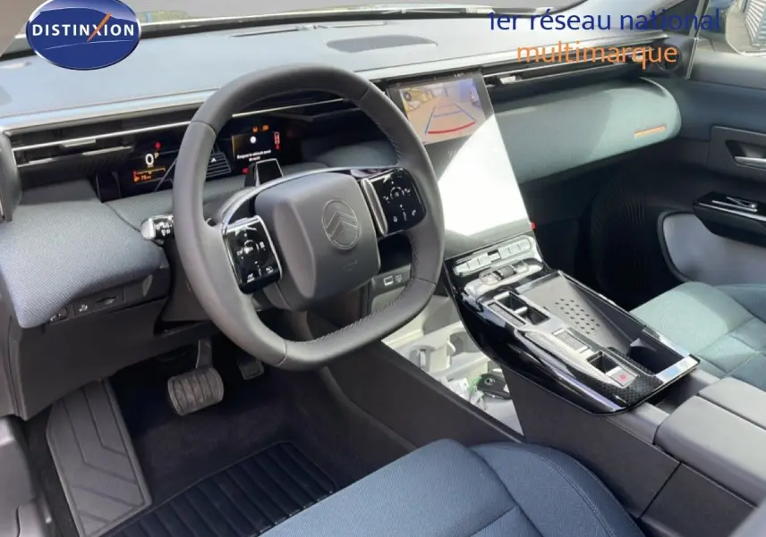 Vue intérieure du tableau de bord et volant du Citroën C5 Aircross Hybrid, avec sellerie tissu bleu et console centrale brillante noire.