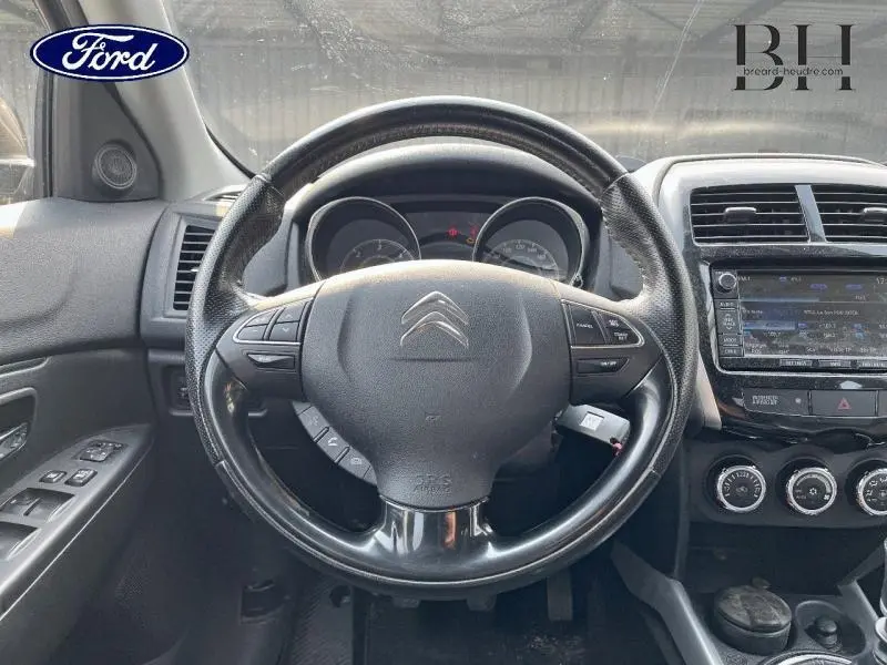 Vue intérieure centrée sur le volant cuir du Citroën C4 Aircross brun Mangaro avec tableau de bord et écran tactile visible.