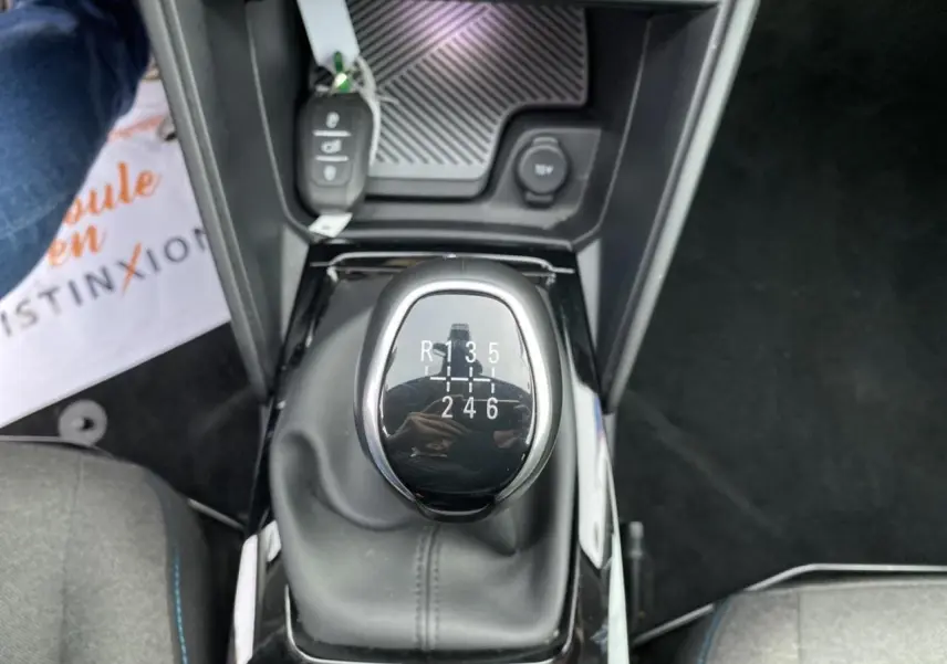 Gros plan sur le levier de vitesses manuel de la Citroën C4 2021, entouré de sièges gris et tapis noirs.