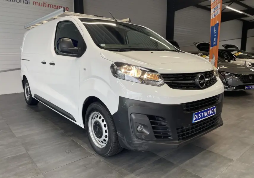 Opel Vivaro blanc en fourgon, vue 3/4 avant droit, avec boucliers noirs et jantes tôles 16 pouces.