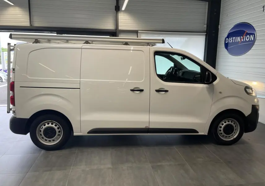 Opel Vivaro blanc en vue profil côté gauche, fourgon utilitaire avec porte latérale coulissante et jantes tôle.
