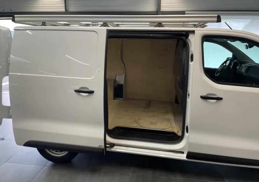 Vue de profil droit d'un Opel Vivaro blanc avec porte latérale coulissante ouverte montrant l'espace de chargement vide.