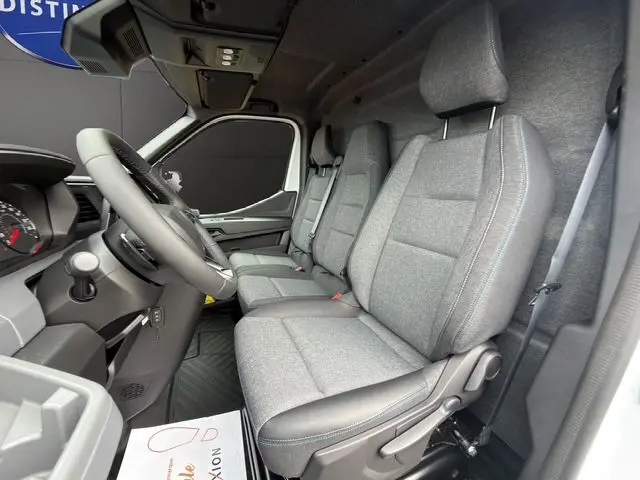 Vue intérieure côté conducteur du Renault Master 2025, montrant la banquette passager grise avec surpiqûres bleues et tableau de bord noir.