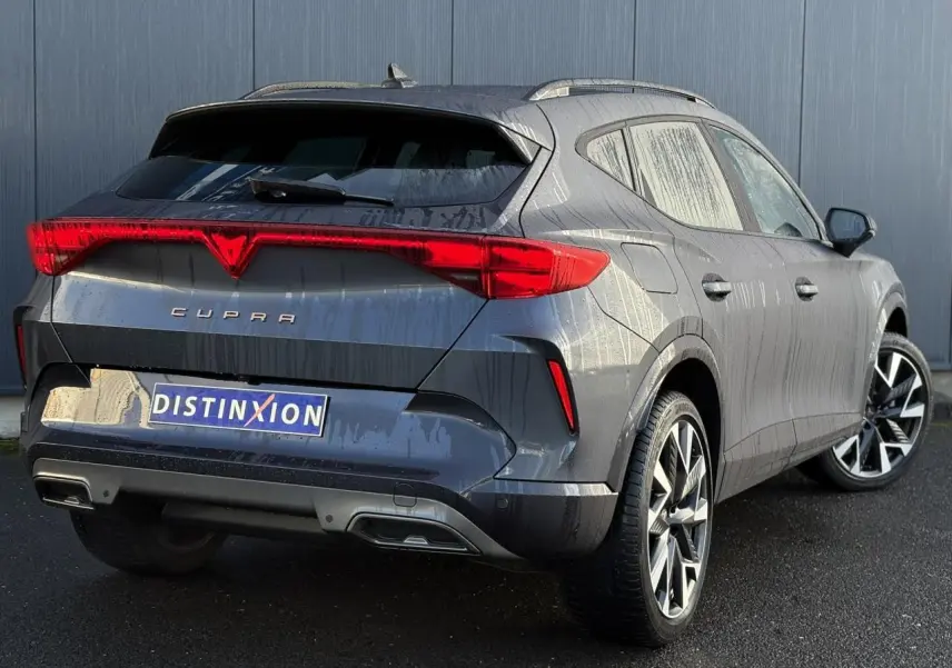 Vue 3/4 arrière droite d'une CUPRA Formentor blanche avec feux arrière en bandeau lumineux et jantes alliage noires et argent.