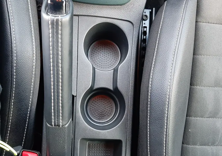 Vue plongeante sur la console centrale noire du SEAT Arona 2025, montrant frein à main, porte-gobelets et siège conducteur.