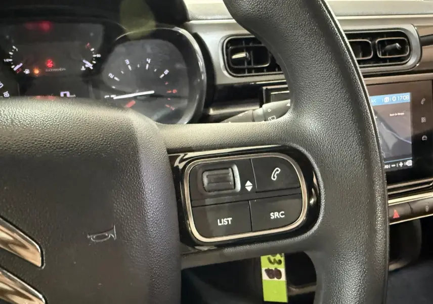 Gros plan sur le volant multifonctions noir de la Citroën C3 2021 avec commandes audio et écran tactile en arrière-plan.