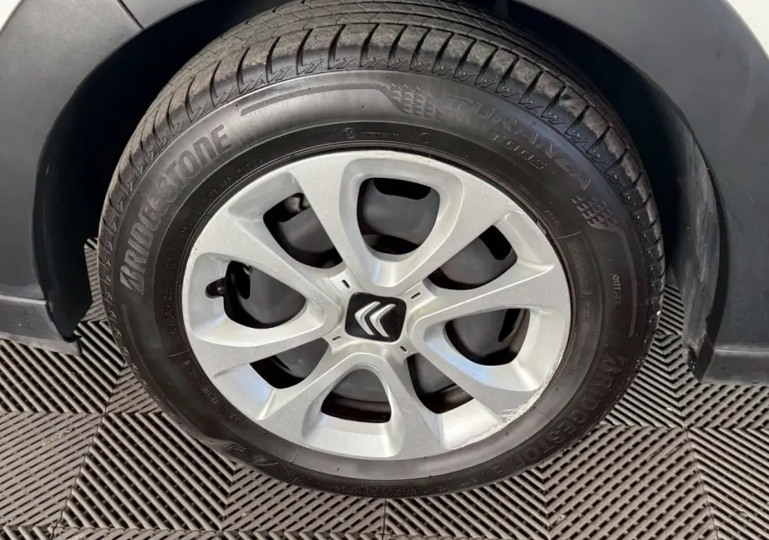 Gros plan sur la roue avant gauche d'une Citroën C3 blanche, jante argentée avec logo Citroën central.