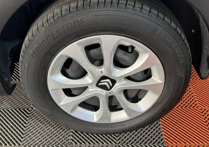 Gros plan sur la roue avant gauche d'une Citroën C3 blanche avec jante argentée et logo Citroën central.