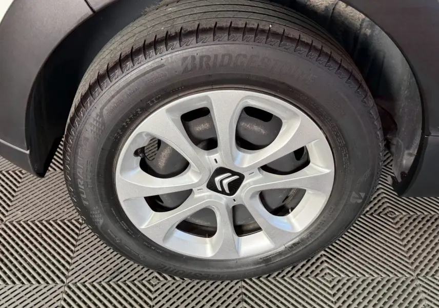 Gros plan sur la roue avant droite d'une Citroën C3 blanche, mettant en valeur la jante alliage et le logo Citroën central.