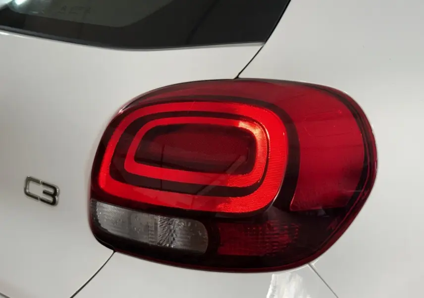 Gros plan sur le feu arrière droit rouge d’une Citroën C3 blanche, avec le logo C3 visible sur la carrosserie.