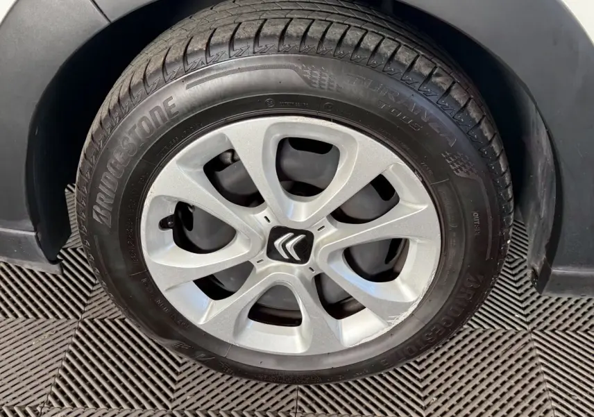 Gros plan sur la roue avant droite d'une Citroën C3 blanche, mettant en valeur la jante avec logo Citroën central.