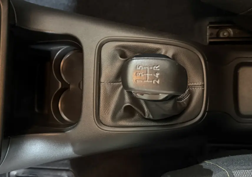 Gros plan sur le levier de vitesses manuel noir de la Citroën C3 blanche, avec console centrale et porte-gobelets visibles.