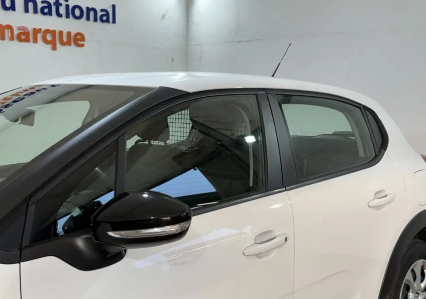 Vue latérale côté gauche d'une Citroën C3 blanche avec rétroviseur noir et poignées de porte assorties.