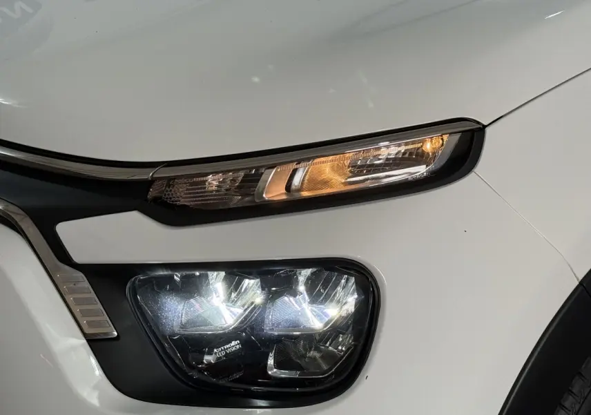 Gros plan sur le phare avant droit blanc de la Citroën C3 2021 avec feux LED allumés et clignotant orange.