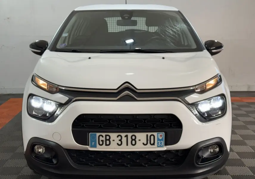 Vue frontale d'une Citroën C3 blanche avec phares LED allumés et calandre noire distinctive.