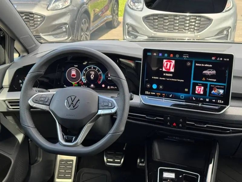Vue intérieure du poste de conduite de la Volkswagen Golf 1.5 eTSI R-Line 2026 avec volant cuir et écran tactile central.