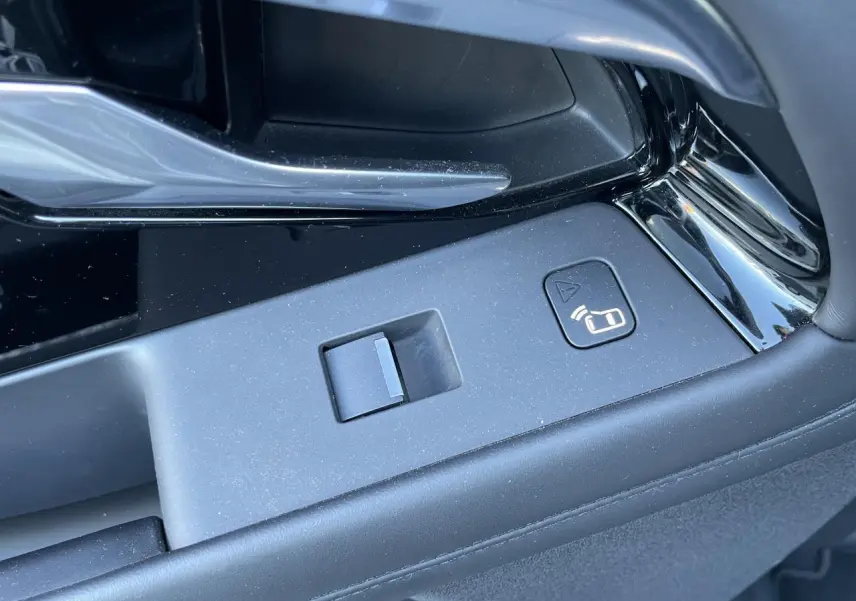 Gros plan sur la commande de verrouillage centralisé dans l'intérieur noir du Range Rover Evoque gris.