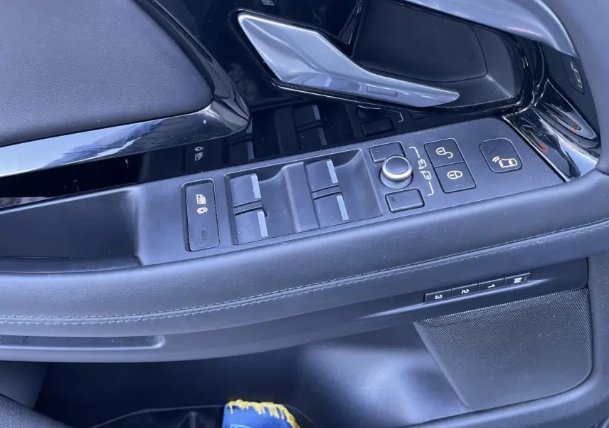 Gros plan sur la porte côté gauche du Range Rover Evoque gris, montrant les commandes des vitres et rétroviseurs.