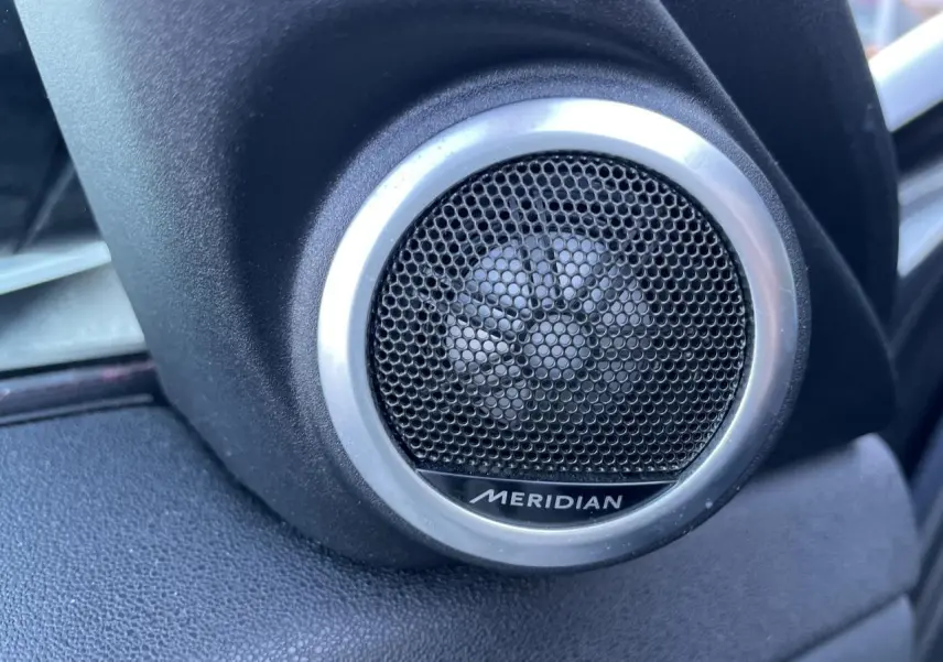 Gros plan sur le haut-parleur Meridian intégré à la porte côté gauche du Range Rover Evoque gris 2019.