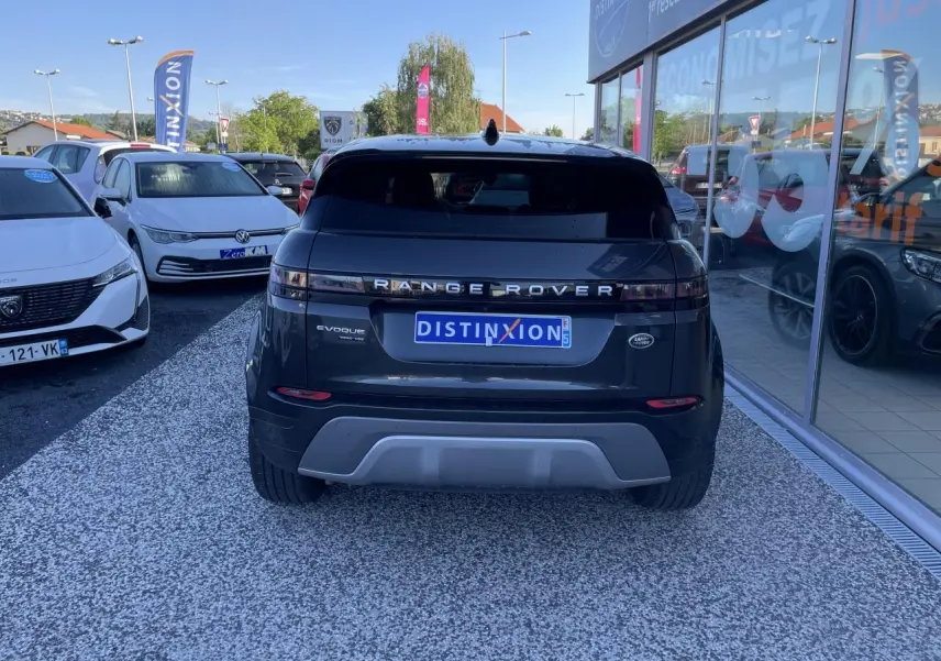 Vue arrière d'un Range Rover Evoque gris métallisé avec logo et plaque Distinxion visible en concession.