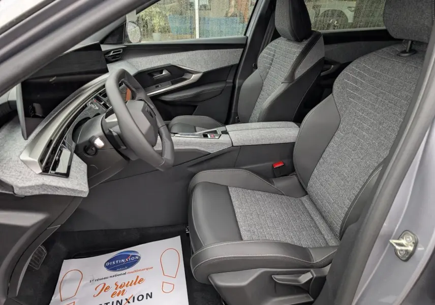 Intérieur côté conducteur du Peugeot 5008 gris Artense 2025, sièges tissu gris et cuir noir, tableau de bord moderne avec écran incurvé.