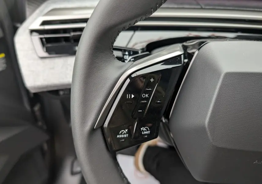 Gros plan sur la partie gauche du volant cuir noir du Peugeot 5008 gris Artense avec commandes intégrées.