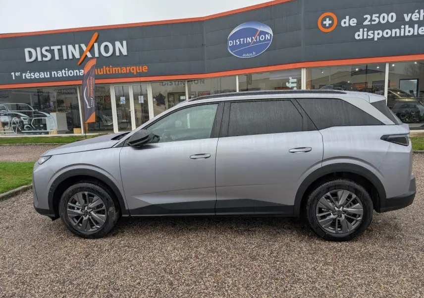 Peugeot 5008 gris Artense vue de profil côté gauche, stationnée devant un concessionnaire Distinxion