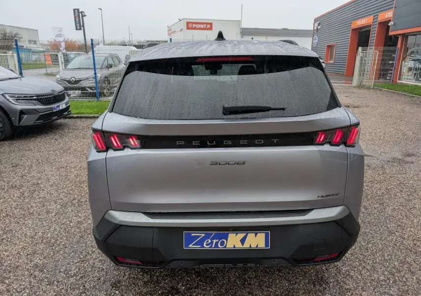Vue arrière sous la pluie d’un Peugeot 5008 gris Artense avec feux arrière à trois griffes LED et bandeau noir laqué.