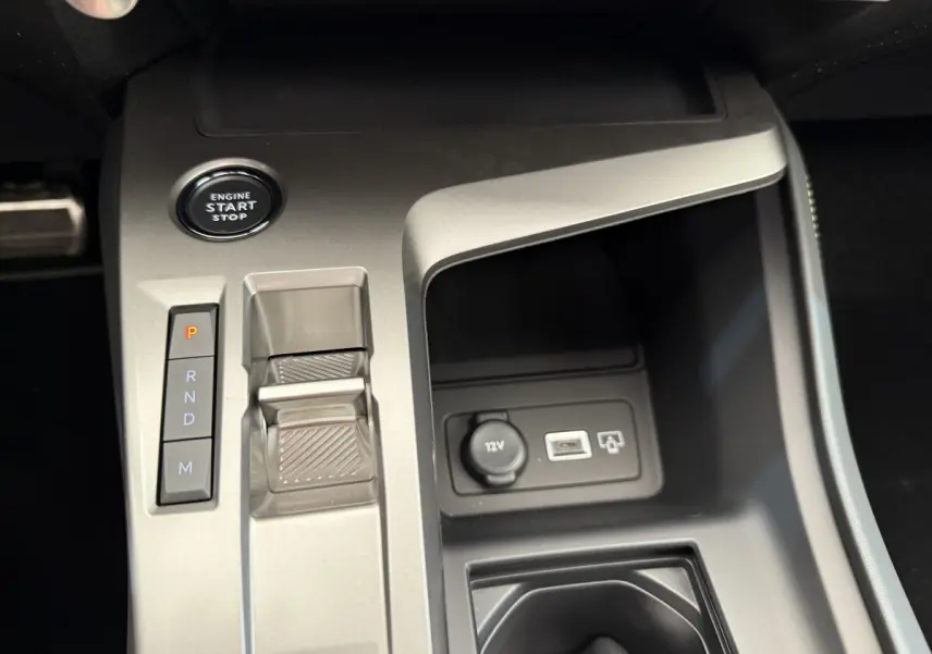Gros plan sur la console centrale grise du Peugeot 308 Hybrid 136 e-DCS6 GT avec bouton start/stop et commandes boîte auto.
