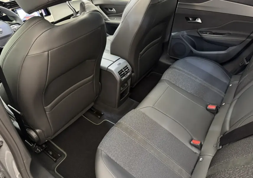 Vue intérieure arrière côté droit de la Peugeot 308 Hybrid gris foncé, montrant les sièges en cuir et tissu et la console centrale.