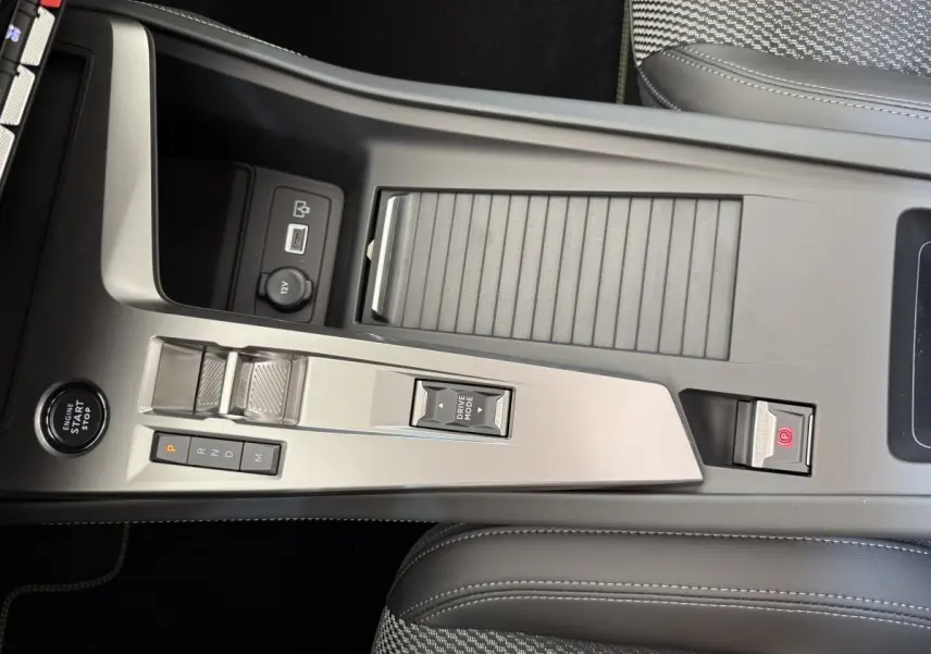 Vue rapprochée de la console centrale gris clair du Peugeot 308 Hybrid 136 e-DCS6 GT avec commandes de boîte auto et bouton start/stop.