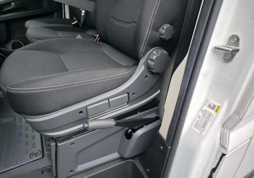 Gros plan sur la banquette biplace noire côté conducteur du Peugeot Boxer Fourgon blanc, avec réglages manuels visibles.