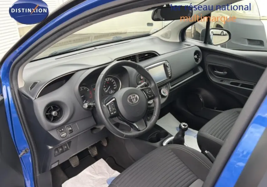 Vue intérieure côté conducteur de la Toyota Yaris MC2 69 VVT-i Design 2018 bleu foncé, volant multifonctions et boîte manuelle visibles.